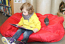Vapaa-aika: lapsi lukee kirjastossa kirjaa. Kuva: Susanna Karhapää